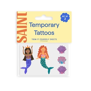 May include: A package of temporary tattoos featuring mermaid and seashell designs. The package includes two sheets of trim-it-yourself tattoos. The mermaids have purple and teal tails, and the seashells are pink and purple.