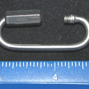 May include: A silver metal hook with a hexagonal head. The hook is about 3 inches long.