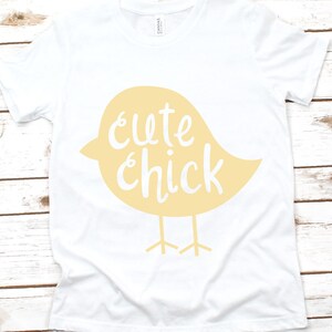May include: White t-shirt with a yellow chick design and the text "cute chick" printed on it.
