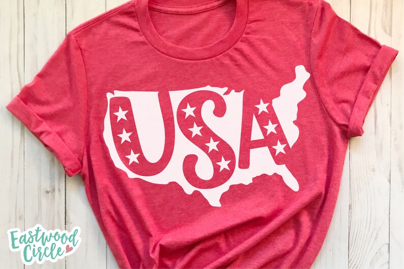 May include: Red t-shirt with a white outline of the United States of America and the word "USA" inside. The letters are decorated with white stars.