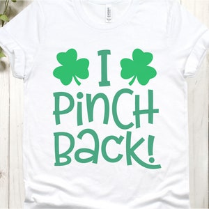 Puede incluir: Camiseta blanca con dise&ntilde;os de tr&eacute;bol verde y el texto "I Pinch Back!"
