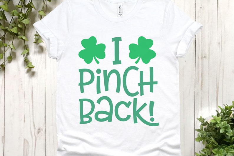 Puede incluir: Camiseta blanca con dise&ntilde;os de tr&eacute;bol verde y el texto "I Pinch Back!"