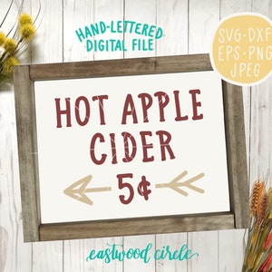 Op de afbeelding: Een rustiek houten bord met de tekst "HOT APPLE CIDER 5&euro;" in rode en bruine letters. Het bord is ingelijst in een bruin houten frame en heeft een witte achtergrond. Het bord staat op een witte houten achtergrond.