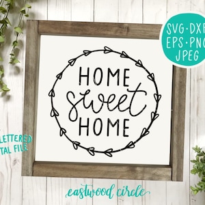 以下が含まれることがあります： 「Home Sweet Home」と手書きで書かれたデザインの白黒デジタルダウンロード。ハートのリースで囲まれた円形です。デザインは白い背景に木製のフレームで飾られています。