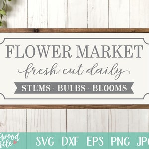 Pu&ograve; includere: Un cartello in legno rustico con sfondo bianco e testo grigio. Il cartello recita "FLOWER MARKET fresh cut daily STEMS BULBS BLOOMS".