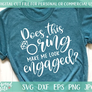 May include: A teal blue t-shirt with white text that reads "Does this ring make me look engaged?"  The text is in a cursive font and includes a stylized diamond ring graphic.