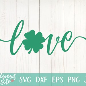 Puede incluir: Un tr&eacute;bol verde con la palabra "love" escrita en cursiva. El dise&ntilde;o est&aacute; sobre un fondo de madera blanca.
