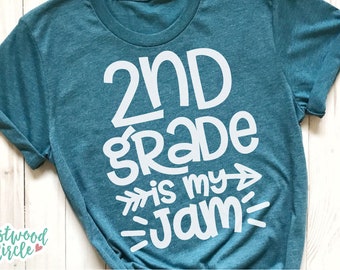 Pode incluir: Camiseta azul turquesa com texto branco que diz "2nd grade is my jam" com uma seta apontando para a direita.