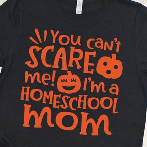 Pu&ograve; includere: Maglietta nera con testo arancione che recita "You can't scare me! I'm a homeschool mom" con una grafica di zucca.