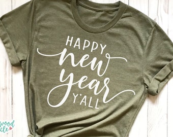 Può includere: Una maglietta verde con il testo "Happy new year y'all" in lettere bianche in corsivo.