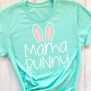 May include: A turquoise t-shirt with white text that says "Mama Bunny" and pink bunny ears.
