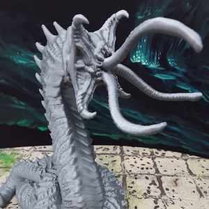 May include: A gray 3D printed miniature of a monstrous creature with tentacles and a segmented body. A red 20-sided die is in front of the creature.