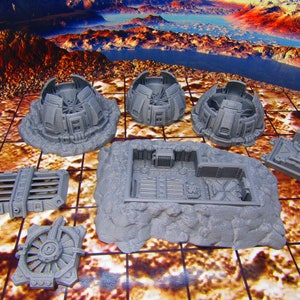 May include: A set of gray plastic model pieces for a sci-fi themed tabletop game. The pieces include a dome-shaped structure, a rectangular building, and several smaller pieces.