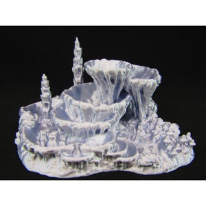 May include: A 3D printed, light blue, abstract sculpture with multiple, rounded, bowl-like shapes and tall, thin, spire-like shapes. The sculpture is set on a textured, rocky base.