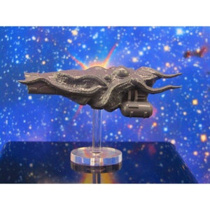 May include: A gray, detailed, 3D printed spaceship model with a tentacle-like design. The model is mounted on a clear plastic stand.