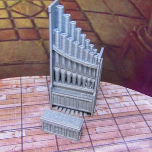 May include: A gray 3D printed miniature pipe organ with a separate bench. The organ has a series of pipes in a curved shape and a keyboard.