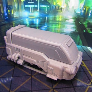 May include: A gray, futuristic-looking vehicle with a boxy design and a rounded front. The vehicle has a detailed exterior with pipes and other mechanical features. It appears to be a model or miniature.