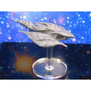 May include: A gray, detailed, spaceship model with a long, pointed nose and a wing-like design. The model is mounted on a clear plastic stand.