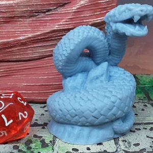 May include: A blue plastic miniature of a two-headed snake with a textured surface. The snake is curled up with its heads raised and open mouths.