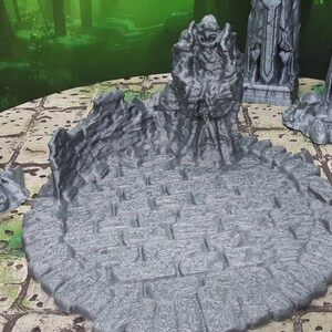 May include: A set of four gray 3D printed miniature statues of warriors holding swords, standing on a gray circular base with a textured surface. The statues are arranged around the base, with one statue in the center.