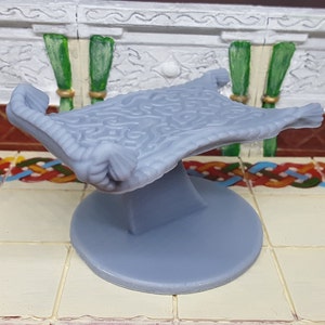 May include: A gray, detailed, patterned rug on a gray base. The rug is curled up on the sides and has a raised, textured design.