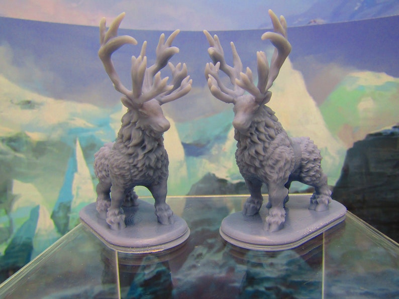 May include: Two gray 3D printed figurines of a deer with large antlers. The deer are standing on a gray base and are facing each other.