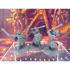 May include: Three gray plastic miniature figures of female warriors holding swords. The figures are standing on round bases.