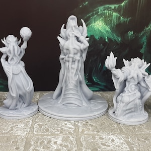 May include: Five gray 3D printed miniature figures of fantasy creatures wearing robes and holding various objects. The figures are posed in a row on a gray tiled surface.