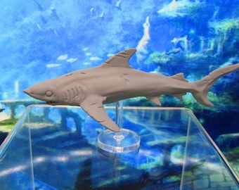 May include: A gray painted shark figurine on a clear plastic stand. The shark has a detailed sculpted body and a textured surface.