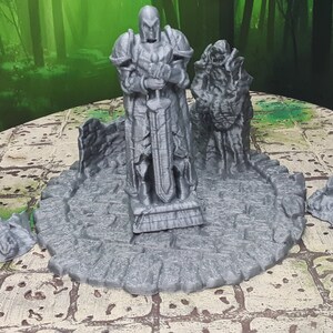 May include: Four gray 3D printed statues of knights, one standing tall with a sword, the other three broken and lying on the ground. The statues are on a circular base with a stone texture.