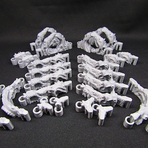 May include: A collection of gray, intricately detailed, 3D-printed miniature fantasy terrain pieces. The set includes archways, curved walls, and other architectural elements, ideal for tabletop gaming or model building.