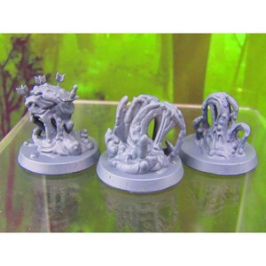 May include: Three gray plastic miniature figures of a creature with tentacles and a face, each on a round base. The figures are painted in a light gray color.