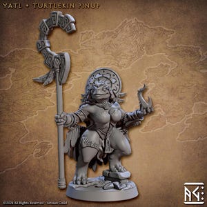May include: A grey painted miniature figurine of a turtlekin woman wearing a feathered headdress and holding a staff and a curved blade. The figurine is standing on a circular base.