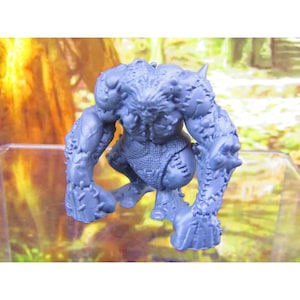 May include: A blue plastic miniature figure of a creature with a spiky, textured body and a rough, woven loincloth. The figure is in a crouching position with its arms outstretched.
