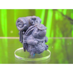 May include: A gray plastic miniature figurine of a creature carrying a large backpack. The creature is wearing a hat and has a round, furry body.