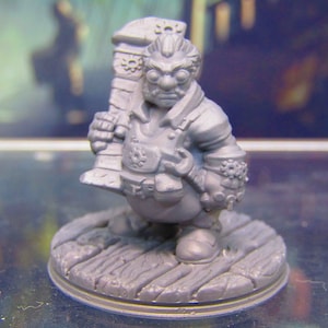 May include: A gray miniature figurine of a steampunk gnome holding a wrench and a large gear. The gnome is wearing goggles and a jacket with gears and other steampunk details. The figurine is standing on a gray base.