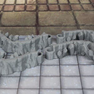 May include: Four gray plastic dungeon wall pieces with a rough, rocky texture. The pieces are designed to be connected together to create a wall or barrier.