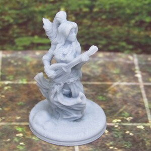 May include: A gray 3D printed miniature of a female figure playing a lute. The figure is wearing a flowing robe and has long hair. The miniature is on a round base.