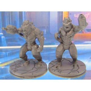 May include: Two gray plastic miniature figures of humanoid creatures with reptilian features. The figures are standing on round bases with a textured surface. One figure is holding a weapon, while the other is holding a cylindrical object.