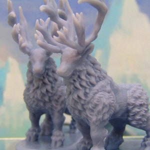May include: Two gray, furry, miniature reindeer figurines with large antlers. The reindeer are standing on a clear base.