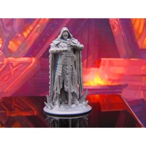 May include: A gray 3D printed miniature of a hooded figure holding a sword. The figure is standing on a round base with a textured surface. The figure is wearing armor and a cloak.