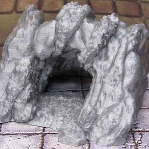 May include: A gray, 3D printed rock formation with a cave opening. The cave is large enough for a small figure to enter.