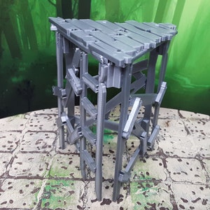 May include: A gray, wooden, triangular-shaped miniature tower with a flat top. The tower is made of planks of wood that are connected together to form a structure. The tower is standing on a gray, tiled surface.