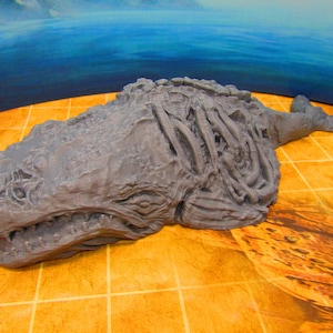 May include: A grey, detailed, 3D printed model of a whale skeleton. The model is lying on a tiled surface.