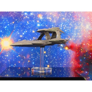 May include: A gray spaceship model with a clear plastic stand. The spaceship has a long, thin body with two wings and a pointed nose. The model is set against a blue and red starry background.