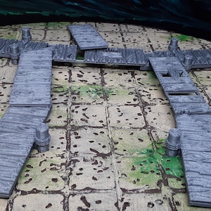 May include: A set of four gray wooden dock pieces for tabletop gaming. The pieces are made of a textured plastic and have a realistic wood grain design. The dock pieces are designed to be used in a tabletop game to represent a dock or pier.