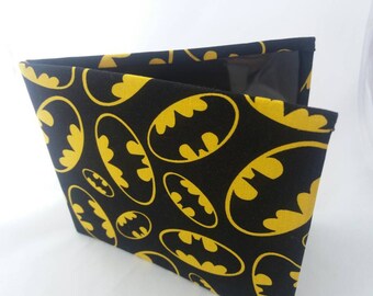 May include: Black fabric wallet with a yellow Batman logo pattern. The wallet has a clear plastic window on the front.