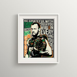 Peut inclure: Une affiche de motivation représentant une illustration en noir et blanc de Conor McGregor, un combattant d'arts martiaux mixtes, sur un fond vert et orange. Le texte sur l'affiche dit "Soyez reconnaissant pour chaque chose que vous faites. Ayez et soyez couronné de succès dans chaque chose que vous faites."