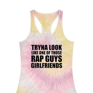 May include: A tie-dye tank top with the text "Tryna look like one of those rap guys girlfriends" in black.