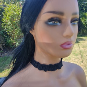 May include: A black crocheted choker necklace. The necklace is made of a soft, delicate yarn and has a simple, elegant design.